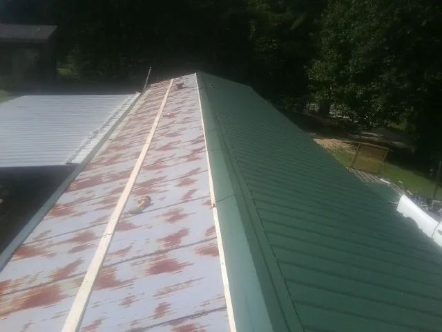 Old rusted panels beside newly installed green metal roofing — Wind Damage Roof Repair by Roofing Brothers in Valdosta
