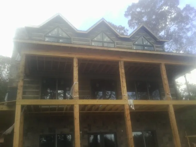 Dormers and porch framing on a large log home under construction — Roof Coating work by our crew in Valdosta
