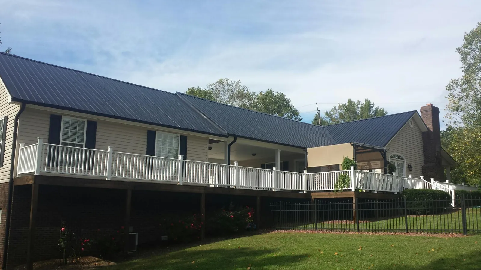 Black metal roof above a long white railed deck on a hillside home in Valdosta