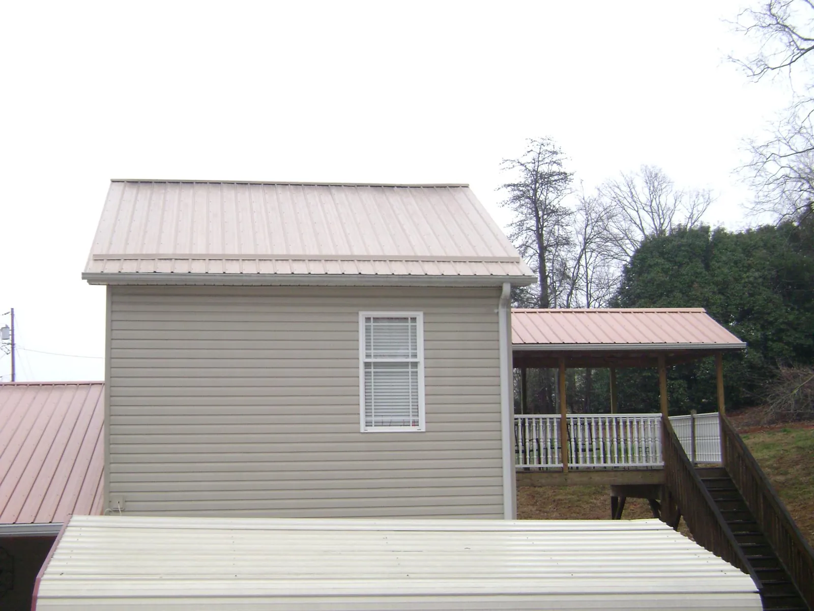 Tan metal roofs on a two story addition and attached porch, from a Roof Replacement job in Valdosta