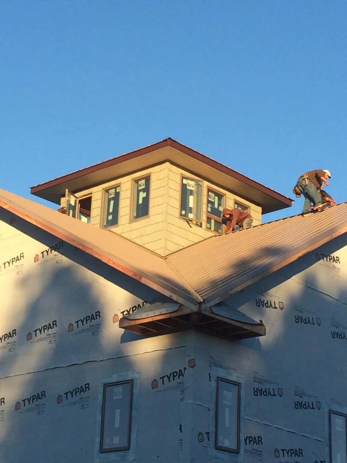 Roofers working around a rooftop cupola on a new metal roof at sunset — Roof Waterproofing in Valdosta by Roofing Brothers